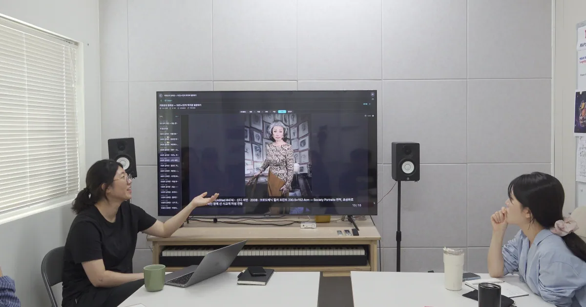 강사가 TV 화면을 가리키며 설명하고 있다.
