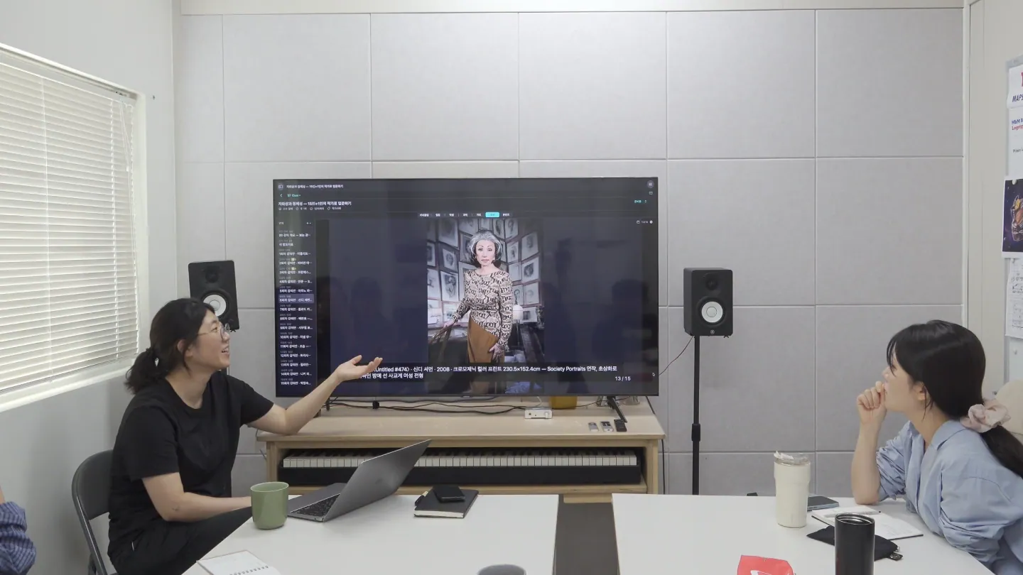 강사가 TV 화면을 가리키며 설명하고 있다.